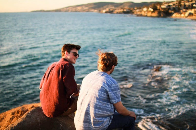 Zwei junge Männer sitzen am Meer und unterhalten sich